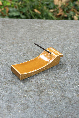 Ceramic incense holder with a stick on a stone surface