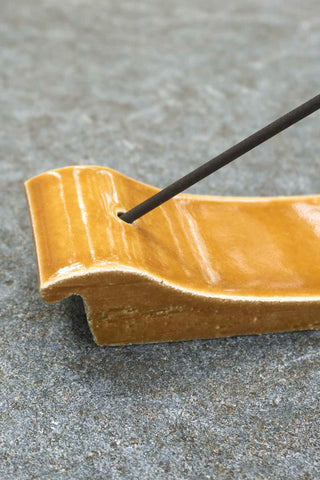 Incense stick in a ceramic holder on a concrete surface