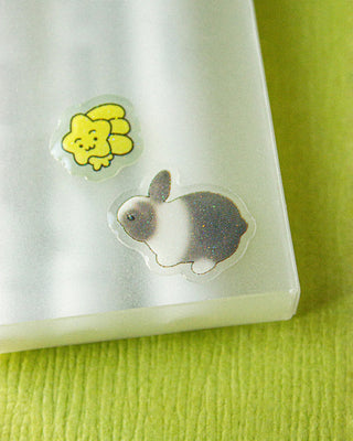 Two cute stickers on a white surface with a green background