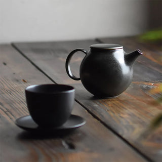 Teapot and matching teacup on saucer on a wooden table