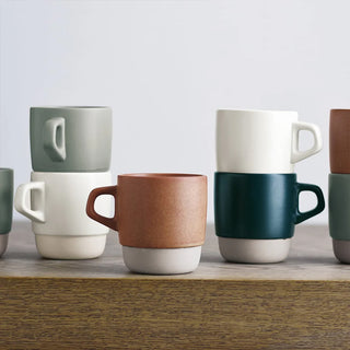Set of colorful ceramic mugs on a wooden surface with a light gray background