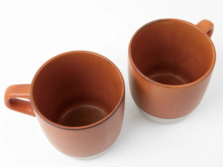 Two orange ceramic mugs on a white background