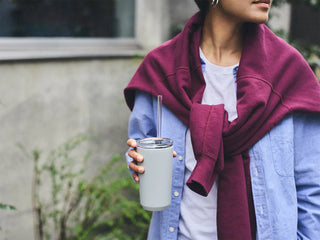 Person holding a insulated tumbler with straw with a blurred background