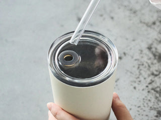 White tumbler with a clear straw on a gray surface