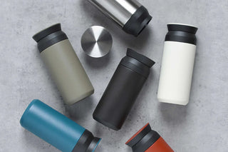 Set of colorful travel mugs on a gray surface