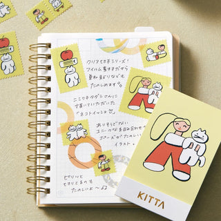 Notebook with Kitta washi tape featuring illustration of girl holding white cat on a beige background