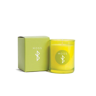 Green candle with 'MOSS' branding next to its green box on a white background