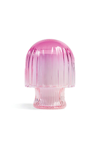 A pink glass blown mushroom candle cloche on a white background