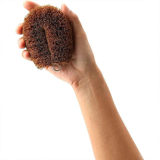 Hand holding a brown scrub against a white background