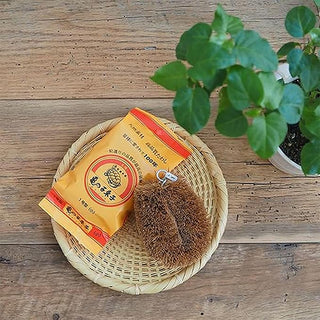 Brown scrubber with yellow packaging on a woven mat on a wooden surface with a plant in the background