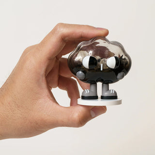 Hand holding a small cloud figurine against a plain background