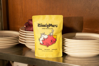 Yellow package of KimlyParc sweet potato latte on a metal surface with white plates in the background.