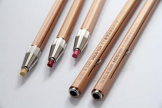 Set of pencils with wooden and metal accents on a light background