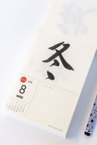 Calendar with Japanese calligraphy and a pen on a white background