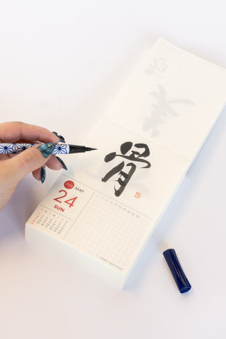 Hand writing calligraphy on a calendar with a pen