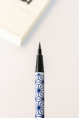 Black calligraphy pen with blue star pattern on a white background