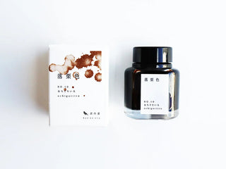 A bottle of ink and white packaging box, featuring brown ink splatter graphics and Japanese text