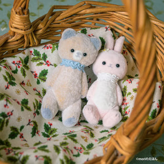 Two plush toys, a bear and a rabbit, sitting in a wicker basket with a floral patterned fabric.