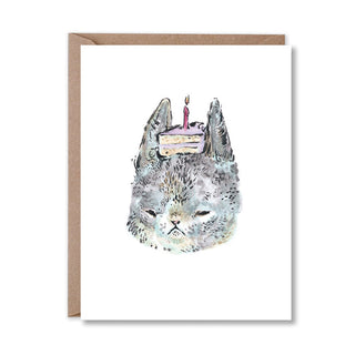 Greeting card with a cat's face with a birthday cake and candle on its head on a white background