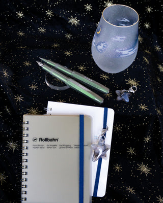 Two green Kaweco pens on a black fabric star background with notebooks
