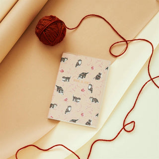 Notebook with cat pattern and ball of yarn on a beige surface