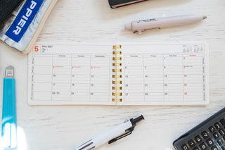 Opened notebook calendar with stationery items scattered around