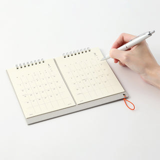 Calendar notebook with a hand holding a pen on a white background