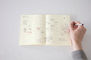 Open notebook planner with person writing in it on a white background