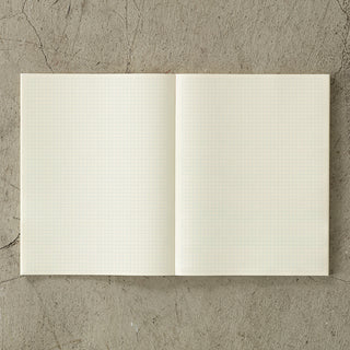 Open notebook with grid pages on a textured stone surface