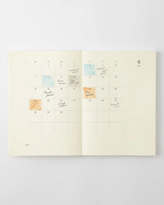opened notebook calendar with june 2027 spread with colorful writing