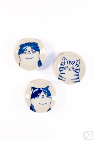 Three circular ceramic plates with blue and white cat designs on a white background