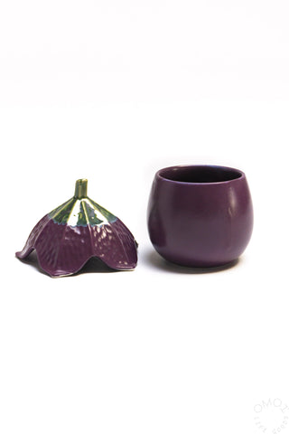 Ceramic eggplant-shaped jar next to its matching lid on a white background