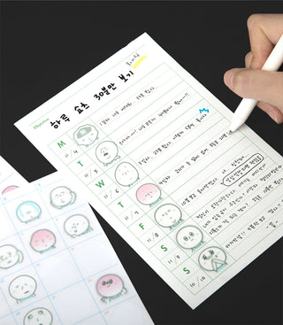 Sheet of paper with Korean text and cartoon character stickers, held by a hand with a pen.