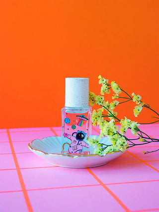 Bottle of small perfume bottle with illustrations on a dish on a pink and orange background
