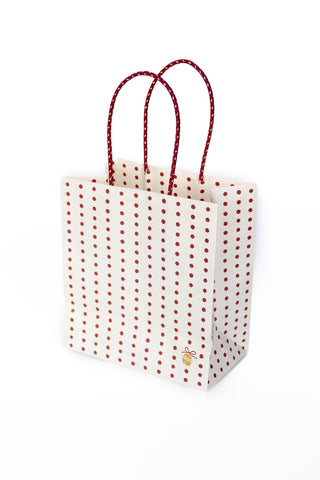 Polka dot gift bag with red handles on a white background