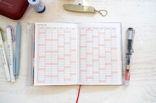 Opened planner showing yearly plan for 2027 with stationery items on a table