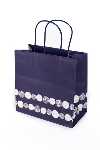 Navy blue paper gift bag with white circular pattern on a white background