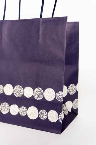 Navy paper bag with white circular patterns on a white background