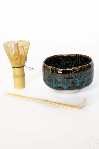 Ceramic tea bowl with bamboo whisk and spoon on a white background