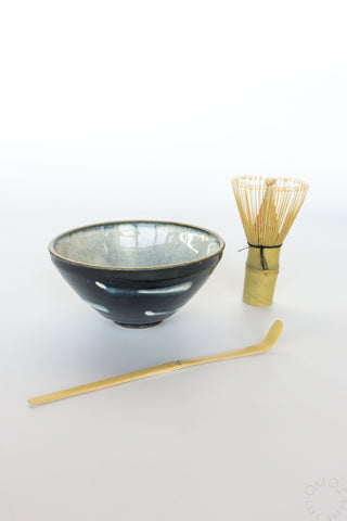 Navy ceramic bowl with a whisk and scoop on a white background