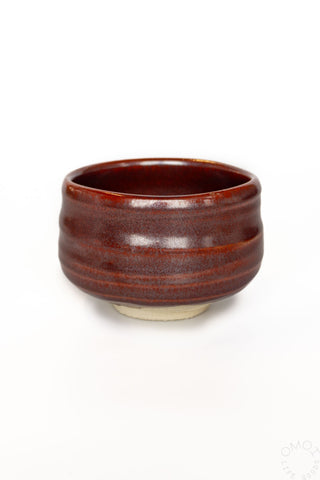 Reddish brown ceramic matcha bowl on a white background