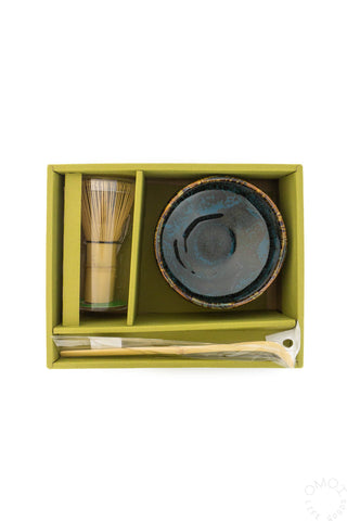 Tea set with bowl, whisk, and spoon in a green box on a white background