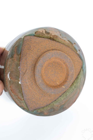 Bottom of ceramic bowl with a textured surface held by a hand on a white background