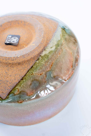 Close-up of a ceramic bowl with a unique glaze pattern on a white background