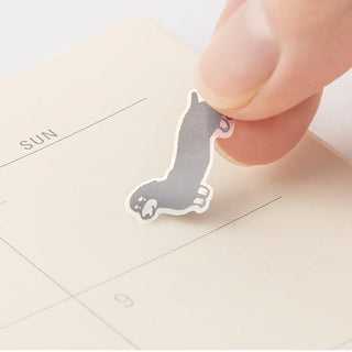 Hand placing a small dog sticker over a calendar