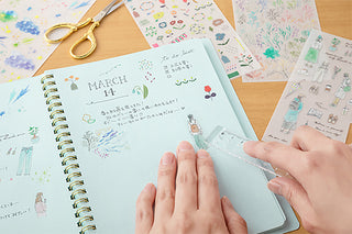 Person using a ruler to put transfer sticker on a notebook