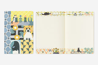 Closed notebook next to open one colorful designs featuring cats and patterns on a white background