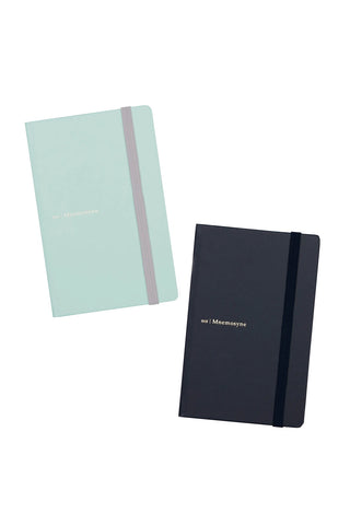 Two hardcover notebooks on a white background, one in mint green with a gray elastic band and the other in dark navy blue with a black elastic band.