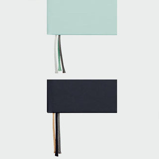 Two notebooks, one mint green and one navy, showing the different colored ribbon bookmarks