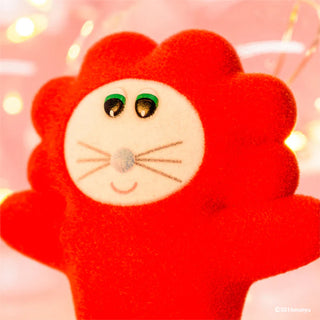 Red plush toy with a smiling face against a blurred light background